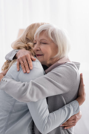 Woman hugging gray haired mom at homeの写真素材