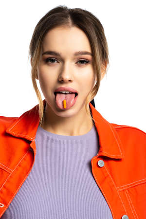 young woman sticking out tongue with capsule isolated on whiteの写真素材