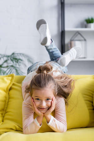 Smiling kid looking at camera on couchの写真素材