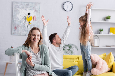 Smiling woman looking at camera near husband and daughter on blurred backgroundの写真素材