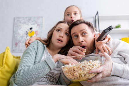 Scared family with popcorn watching film on couch