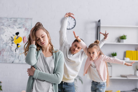 Tired woman standing near husband and kid on blurred backgroundの写真素材