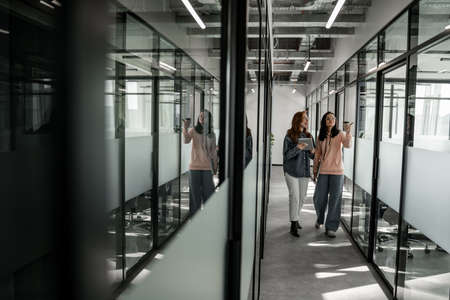 full length of pretty students smiling while walking in hallの写真素材