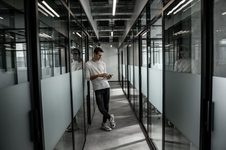 full length of student standing in hall and using digital tabletの写真素材