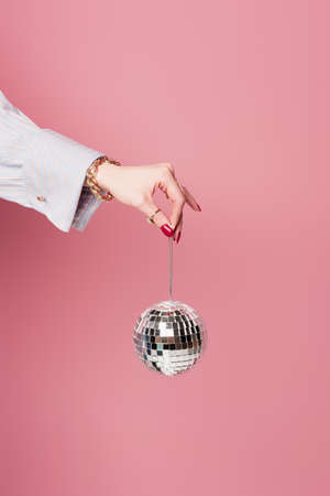 Cropped view of woman with accessories holding disco ball isolated on pinkの写真素材