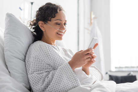 smiling african american woman messaging on mobile phone in hospitalの写真素材