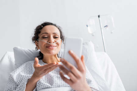 cheerful african american woman pointing at mobile phone on blurred foregroundの写真素材