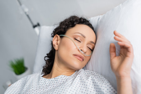 ill african american woman with nasal cannula sleeping in hospital bedの写真素材