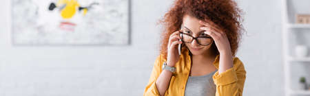 thoughtful freelancer touching head while talking on mobile phone, bannerの写真素材