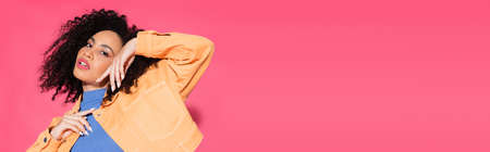 stylish african american woman in jacket posing on pink, bannerの写真素材