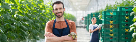 happy farmer smiling at camera near african american colleague on blurred background, bannerの写真素材