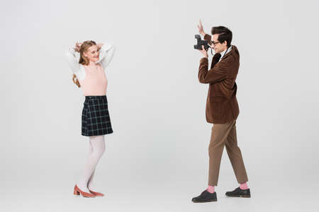 pretty woman in retro outfit posing near man with vintage camera on gray