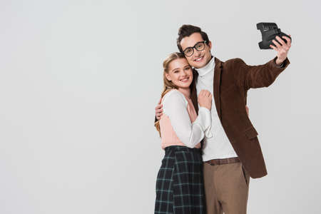 young, old fashioned couple taking selfie on vintage camera isolated on grayの写真素材