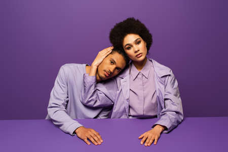african american man leaning on curly young woman isolated on purpleの写真素材