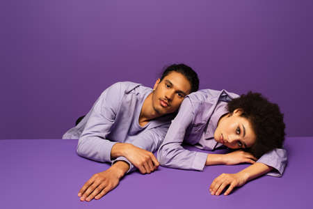 young african american man leaning on woman isolated on purpleの写真素材