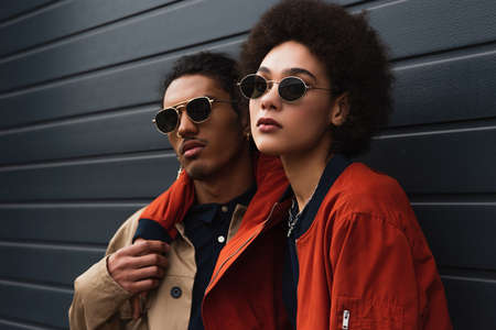 young african american woman posing with stylish man in sunglasses outsideの写真素材