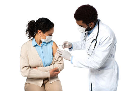 African american doctor doing injection with vaccine to patient in medical mask isolated on white