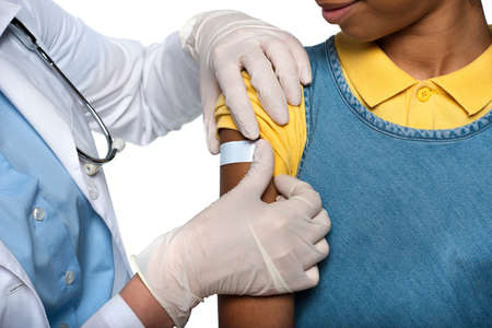 Cropped view of pediatrician applying adhesive plaster on arm of african american patient isolated...