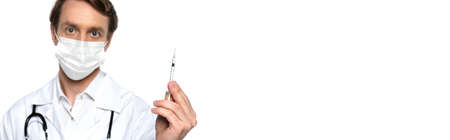 Blurred doctor in medical mask holding syringe isolated on white, bannerの写真素材