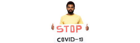 African american man holding placard with stop covid-2019 lettering isolated on white, bannerの写真素材