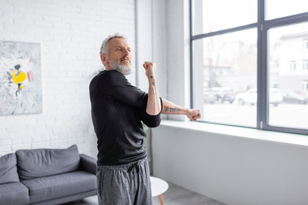 bearded and tattooed man exercising in living room