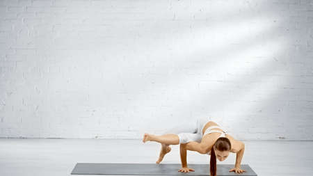 Barefoot sportswoman standing on hands on yoga mat