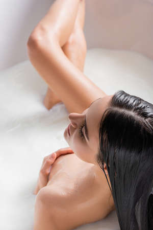 overhead view of sensual woman covering breast while taking milk bathの写真素材