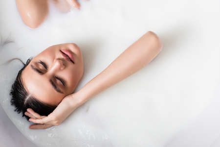 top view of woman with closed eyes relaxing in bath with milkの写真素材