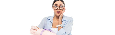 shocked woman looking at camera while holding infant child isolated on white, bannerの写真素材