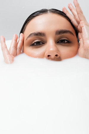 young woman looking at camera while immersing in milk bathの写真素材