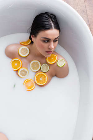young woman taking milk bath with sliced lemon, lime and orangeの写真素材