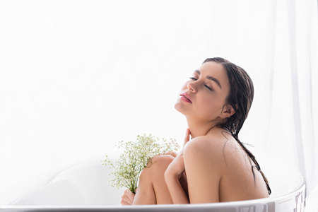 pretty woman bathing with closed eyes and white, tiny flowersの写真素材
