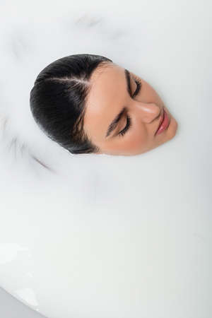 overhead view of woman with closed eyes taking milk bathの写真素材