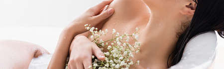 partial view of woman with white flowers enjoying milk bath, bannerの写真素材