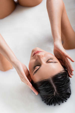 seductive woman touching hair while relaxing in milk bathの写真素材