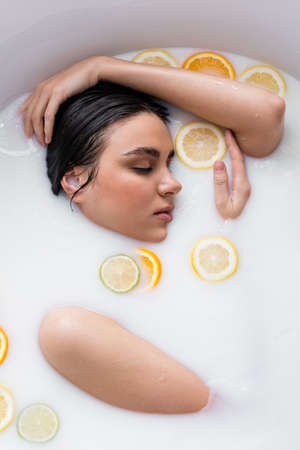 young woman bathing in milk with fresh, sliced citrusesの写真素材