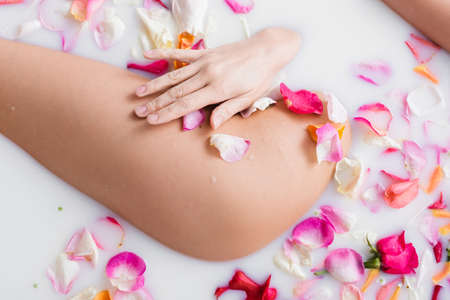 partial view of young woman enjoying bathing in milk with rose petalsの写真素材