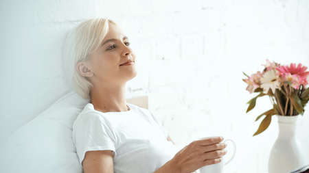 pleased young woman holding cup of coffee at home