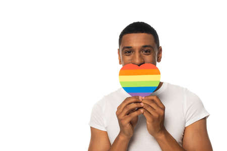african american man covering mouth with rainbow colors paper heart isolated on white, lgbt conceptの写真素材
