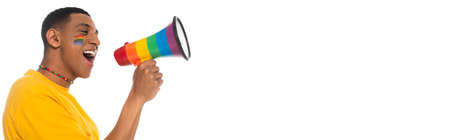 african american man with lgbt flag painted on face shouting in loudspeaker isolated on white, bannerの写真素材