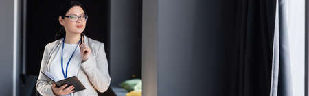 Asian businesswoman holding pen and notebook in office, banner