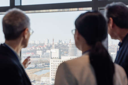 Blurred business people looking at cityscape from officeの写真素材