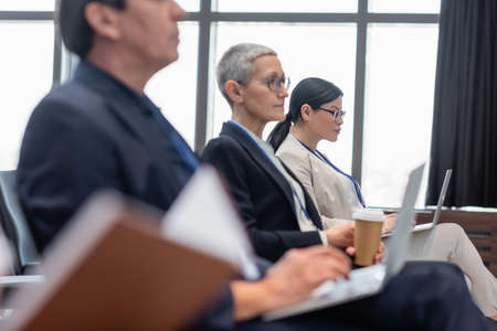 Asian businesswoman using laptop near blurred colleagues in conference roomの写真素材
