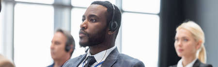 African american businessman in headset near blurred colleagues, banner