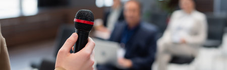 lecturer holding microphone near blurred audience during seminar, bannerの写真素材