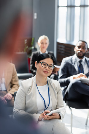 interracial business people listening to lecturer on blurred foreground