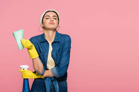 Tired housewife with rag and detergent isolated on pink