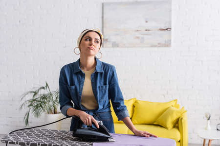 Upset housewife ironing clothes in living room