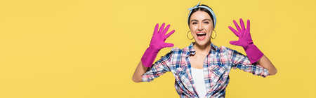 Happy housewife in rubber gloves isolated on yellow, bannerの写真素材