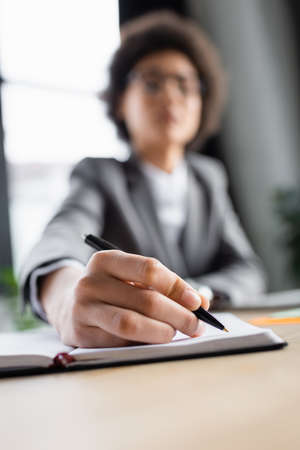 Blurred businesswoman writing on copy book in officeの写真素材